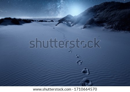 On the beach with the footprints and stars in the sky on the horizon. Milky way