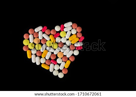 Many different pills and tablets folded in shape of heart on black background. Many pills and tablets with space for text. Health care. Top view. Copy space. New image. Pharmaceutical picture