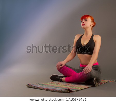 Young girl in sportswear doing yoga on a dark background