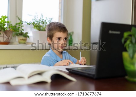 A schoolboy studies at home and does homework. Home distance learning. A boy learns math during his online home lesson, social distance during quarantine, self-isolation, online concept of schoolchild