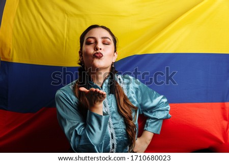 Colombian lady kissing and dancing against national flag of Colombia