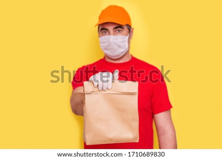 A courier employee in uniform holds a cardboard box with food isolated. Service quarantine pandemic coronavirus. 