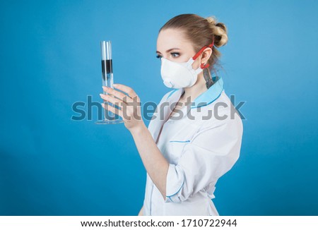 beautiful woman doctor in protective mask against coronavirus on a blue background in the Studio