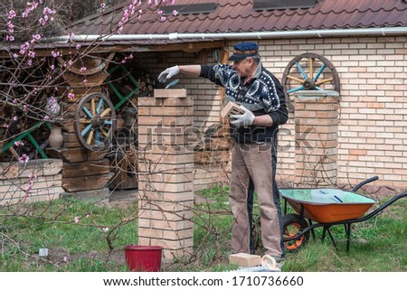 Elderly man is engaged in a hobby of construction and work in the yard.