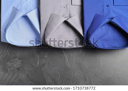 Stylish shirts on grey stone table, flat lay with space for text. Dry-cleaning service