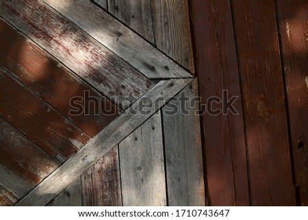 Abstract textured background. Old brown wooden painted surface from cracked boards. The texture of a wooden board. Sun rays fall on an old wooden surface. Close-up, free space, horizontal.