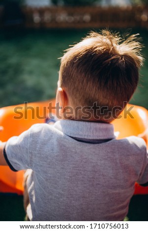 Little boy on top of slide at the playground getting ready to go down to the bottom where it awaits a father who wants to catch him