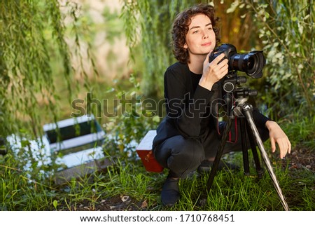 Young woman as landscape photographer with camera and tripod as hobby