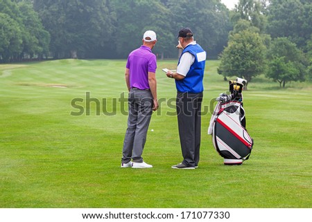Caddy pointing out a hazard to the golfer on a par 4 fairway Royalty-Free Stock Photo #171077330