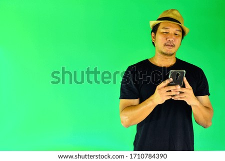 Portrait of a Asian young man use a smartphone on over green screen background