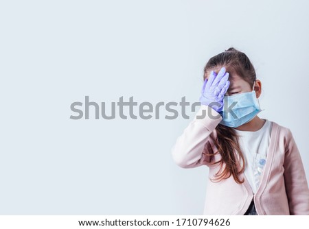 Little girl in medical mask making facepalm with COVID-19 word. Coronavirus concept.