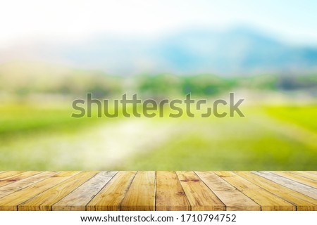 Shelf of Brown wood plank board with blurred green rice field farm with mountain and hut nature background.