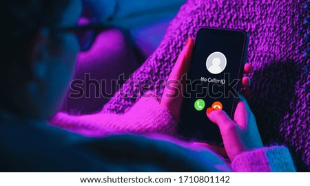 Phone call from no caller id late at night. Scam, fraud or phishing with smartphone concept. Prank caller, scammer or stranger. Woman answering to incoming call. Hoax person with fake identity. Royalty-Free Stock Photo #1710801142