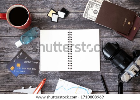 Notebooks and cameras with travel tools placed on a wooden table. top view