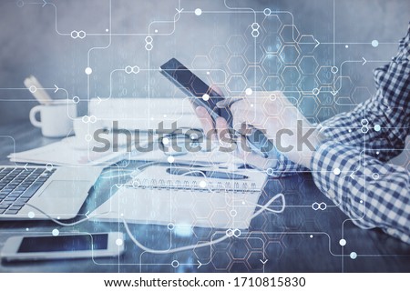 Double exposure of man's hand holding and using a digital device and data theme hologram drawing. Technology concept.