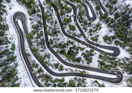 Aerial view of a car serpentine on a mountain. Road to La Thuile village and ski area. Snowy mountain serpentine in Aosta valley in Italy. Royalty-Free Stock Photo #1710823279