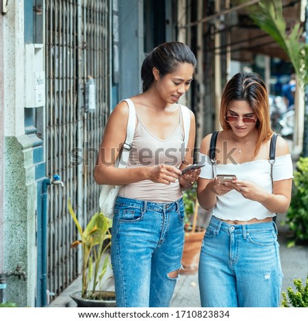 Two friends looking at phone on street stock photo