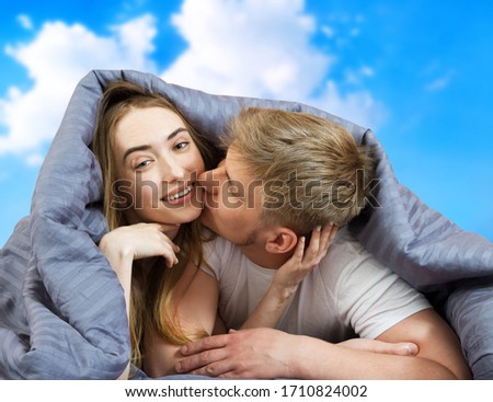 Happy beautiful couple in bed isolated on blue sky background, stay at home concept, coronavirus quarantine background, self isolation, life style at home