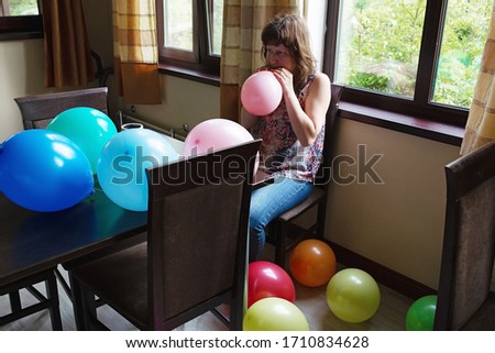 A woman in the room inflates balloons for a holiday