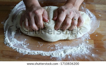 Cooking concept. Female hands preparing fresh homemade pizza dough on floured wooden board. Closeup. Italian cuisine.