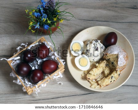 Easter cake, cottage cheese with raisins, fresh egg with yolk, colored egg in a plate, a bunch of spring flowers, natural colored eggs on a wooden table  closeup, top view. Bright picture of Easter