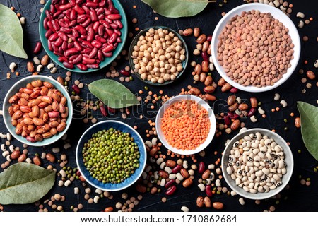 Legumes assortment, shot from the top on a black background. Lentils, soybeans, chickpeas, red kidney beans, a vatiety of pulses Royalty-Free Stock Photo #1710862684