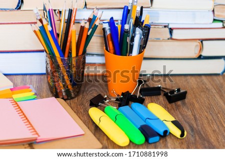School stationery accessories - notebook, copybook stack with plastic holder pencils, pens, markers, paper clips, stickers, notepads, sharpener with stack of books education concept background