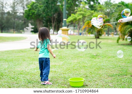 Lovely active little asian girl playing with soap bubble outdoor in the park