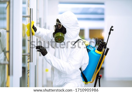 Cleaning and disinfection of office to prevent COVID-19, Man in protective hazmat suit washes office furniture to preventing the spread of coronavirus, pandemic in quarantine city. Royalty-Free Stock Photo #1710905986