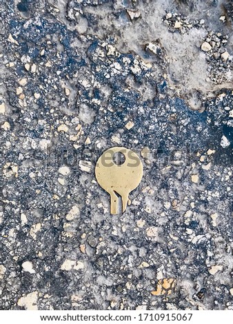 Part of the broken yellow key on the grey pavement 