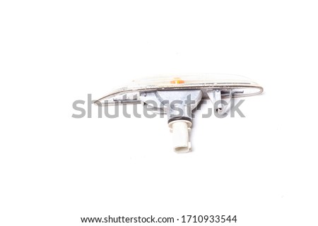 The spare part of the car is a plastic transparent turn signal with a tinted glass of orange color with mounts on a white background. Rear view of auto repair equipment after a collision.