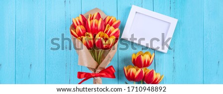 Mother's Day background, tulip flower bunch - Beautiful Red, yellow bouquet isolated on blue wooden table, top view, flat lay, mock up design.