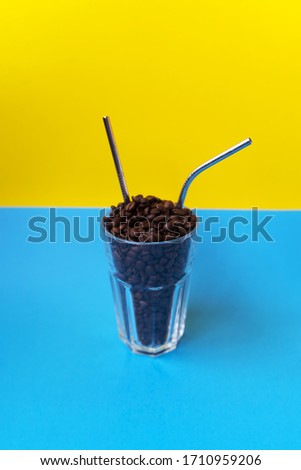 The glass with coffee beans and two reusable steel straws on the light green and dark green background. Plastic free concept. Save the Earth. Copy space. Creative background