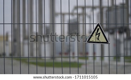 Warning sign on fence in front of high voltage transformer. Hazard Sign High Voltage.
