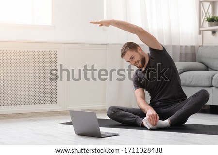 Quarantine sport. Young man practicing fitness with online training on laptop, free space Royalty-Free Stock Photo #1711028488