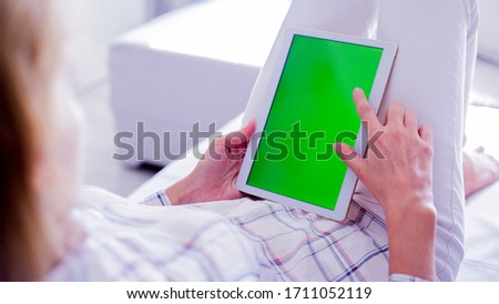Woman is relaxing on comfortable couch and using tablet at home