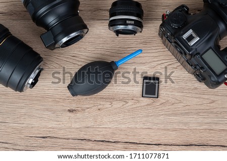 memory card, digital camera, dslr and body black camera placed on a wooden table