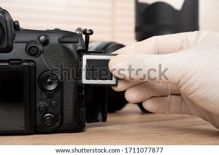The photographer's hand captures memory. black dlsr digital camera card inserted in the slot of the camera