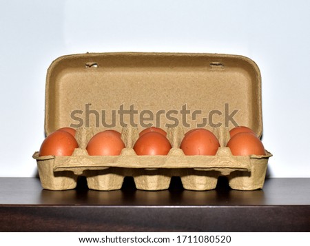 Close up of Fresh Chicken eggs placed in a row in a paper pickup on the wooden table.
