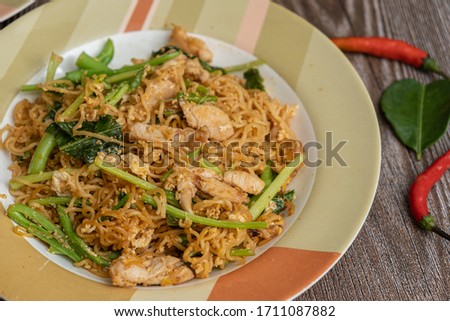 Spicy Fried Noodles with chicken on wooden table - Stock photo