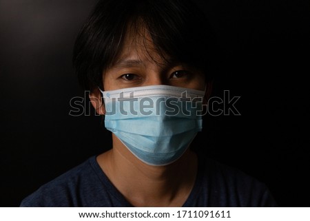Man wearing protection face mask against coronavirus or COVID-19 in darken tone. Banner with copyspace for medical concept