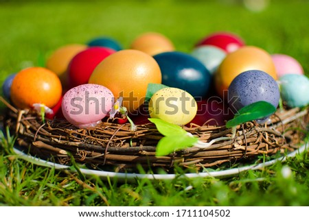 Easter eggs pictured outdoors in a basket on grass.