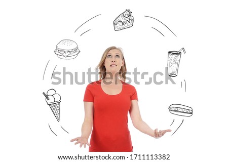 young and attractive blonde woman juggling multitudes of different fatty and sweet foods on white isolated studio background
