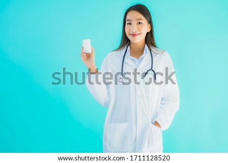 Portrait beautiful young asian doctor woman with drug medicine bottle on blue isolated background