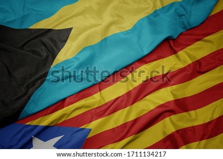 waving colorful flag of catalonia and national flag of bahamas. macro