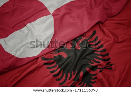 waving colorful flag of albania and national flag of greenland. macro