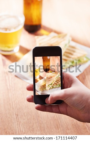Smartphone taking photo of feta cheese sandwich on a restaurant