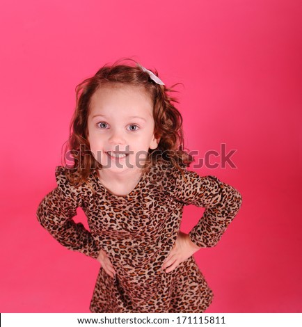 Cute baby girl posing in studio wearing leopard print dress over pink background
