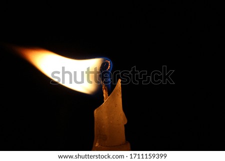 Candle blowing in the dark where the air strike but the flare keeps it glowing