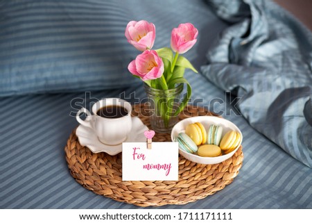 Mothers Day. Breakfast in bed for mom. Breakfast in bed with a map and a cup of coffee. Macarons with a cup of coffee. Good morning. Greeting card for mom. Tulips Unmade pastel with breakfast 